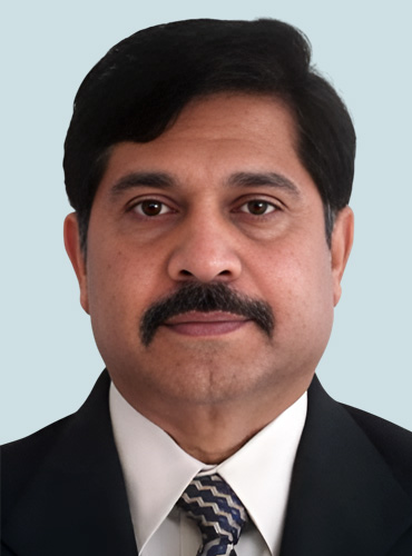 Dr. Aravinda Shetty with a mustache wearing a formal tie, smiling confidently against a neutral background.