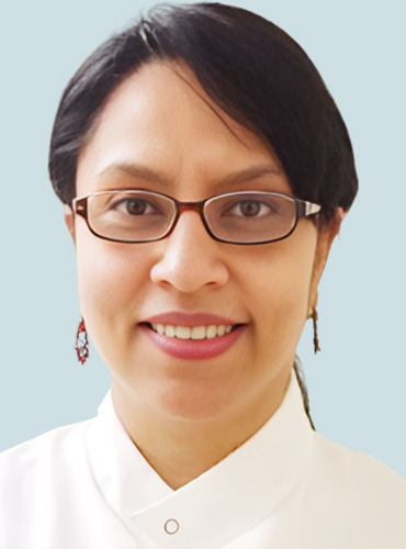 A woman with glasses wearing a white shirt, smiling softly at the camera.