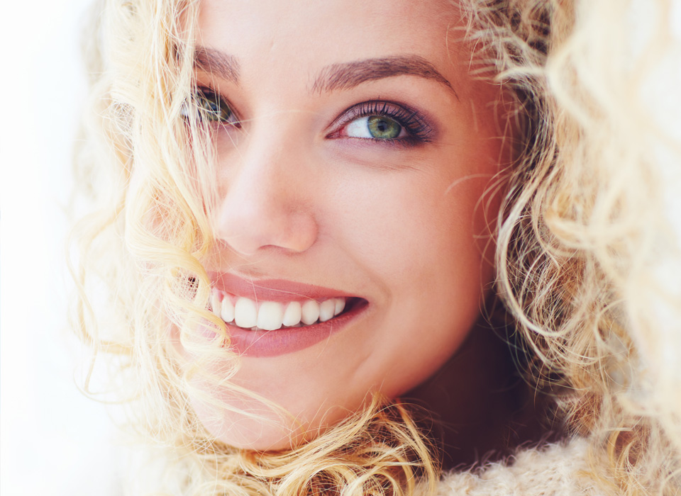 A woman with curly hair dressed in a white sweater, exuding warmth and approachability.